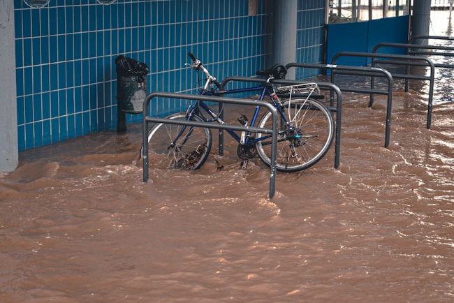 Una bicicleta aparcada en el parking en una calle llena de agua inundada por la lluvia