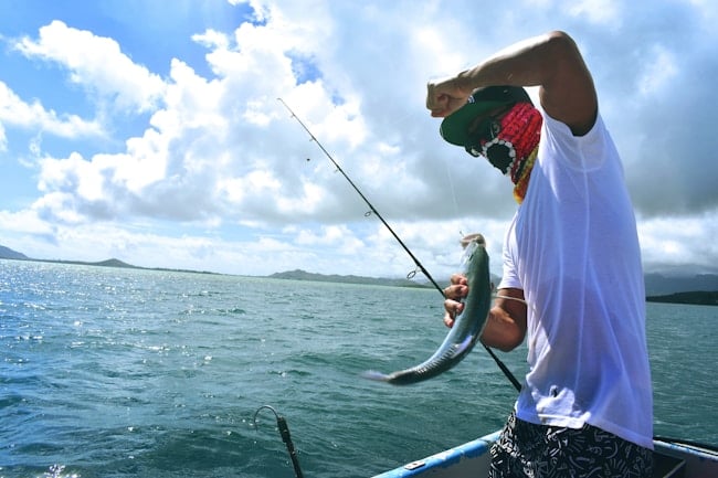 Un garçon montre un poisson qu'il a attrapé avec sa canne à pêche. 